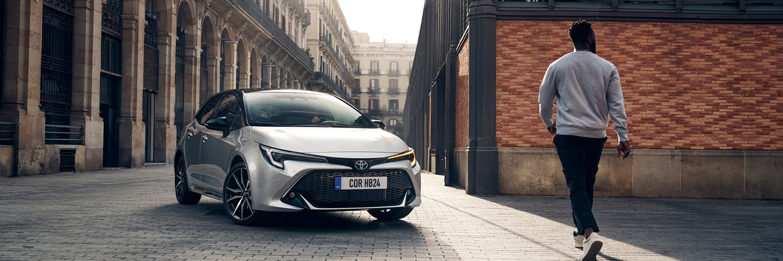 toyota-corolla-hatchback-exterieur-driekwart-rechtsvoor-met-persoon-zilvergrijs